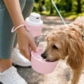 Cane che beve durante la passeggiata dalla borraccia da viaggio rosa