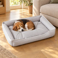 Beagle che dorme acciambellato nella cuccia per cani grigia in tessuto Oxford 600D, in salotto accanto al divano