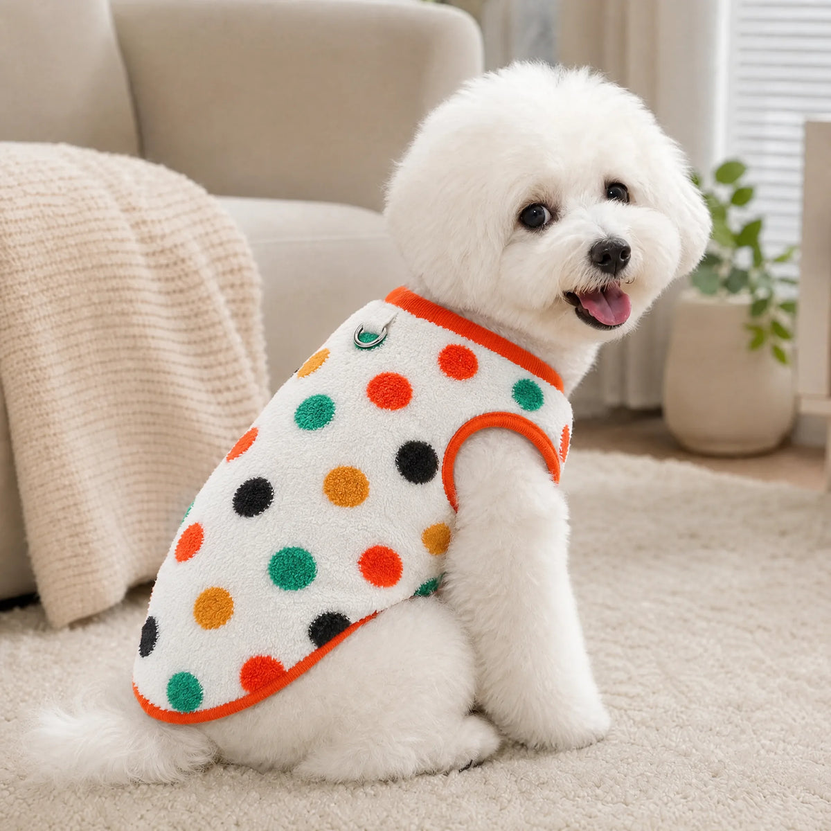 Cane seduto in casa con il pigiama in flanella teddy bianco a pois colorati
