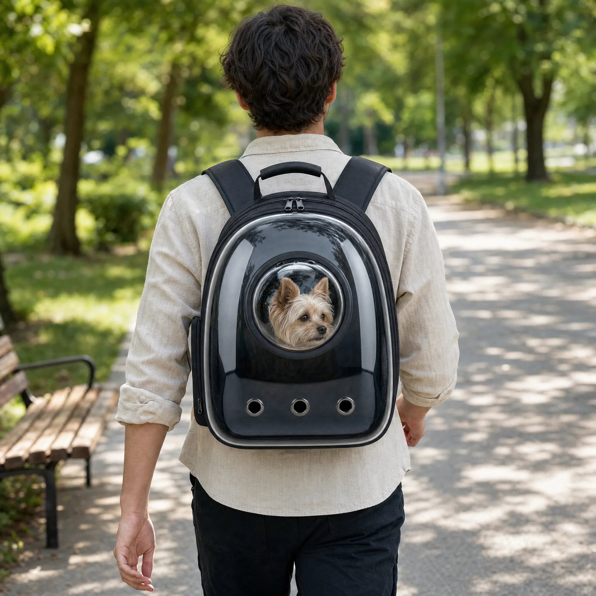 Uomo passeggia nel parco con lo zaino trasportino a capsula spaziale, cagnolino che guarda fuori dall'oblò